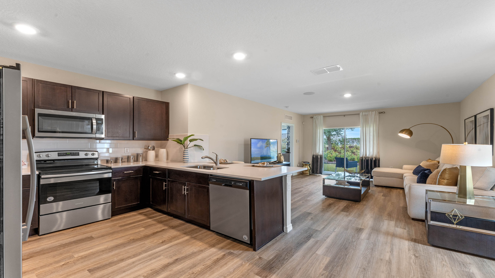 Kitchen with island seating, quartz counters, spacious pantry and stainless-steel appliances.