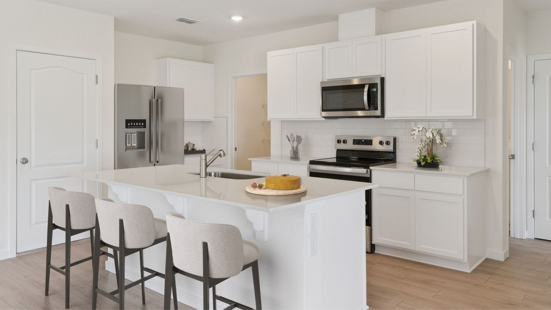 Kitchen with island seating, quartz counters, spacious pantry and stainless steel appliances.