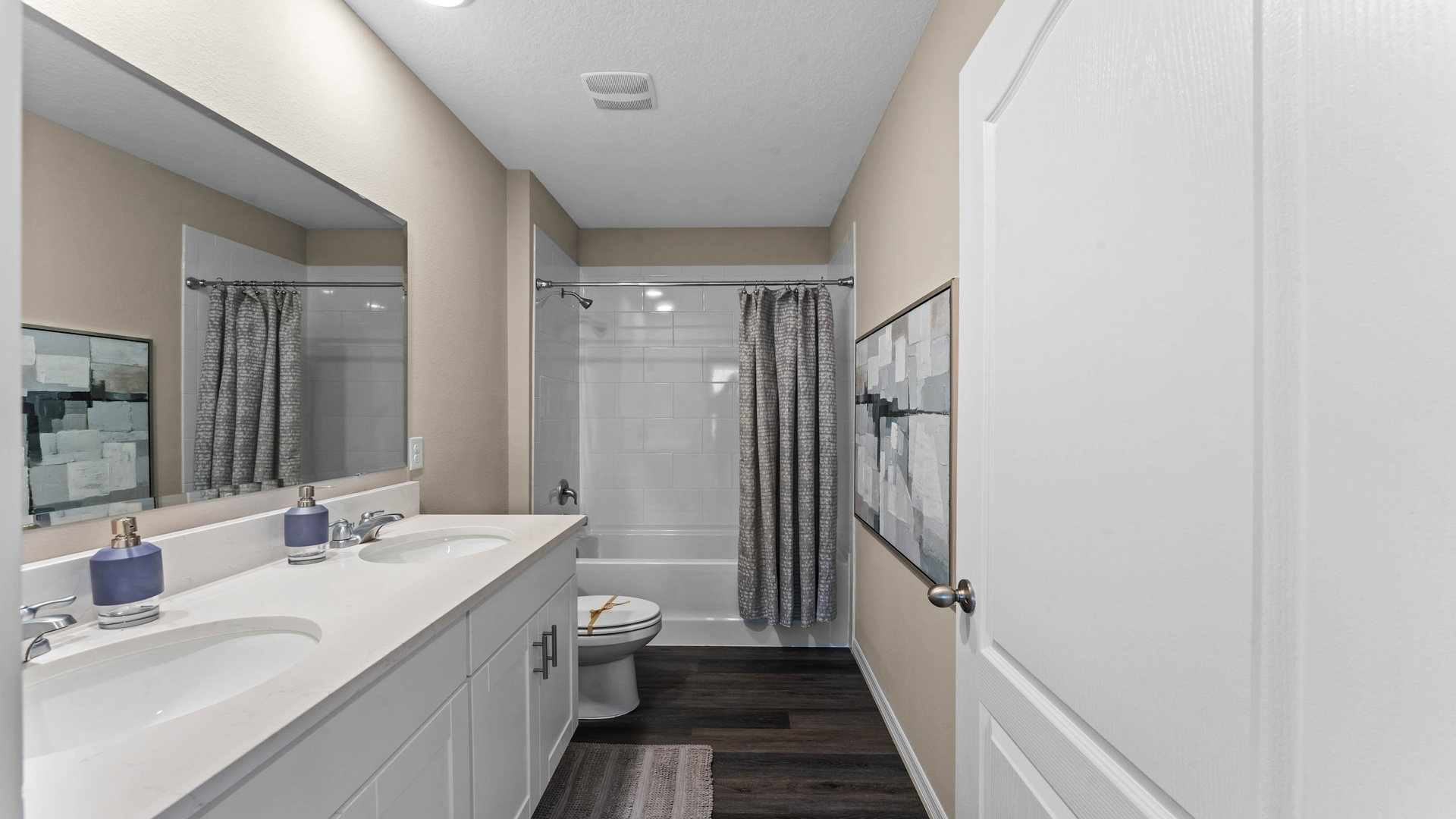 Modern bathroom with double vanity, large wall mirror, cabinets and quartz countertops