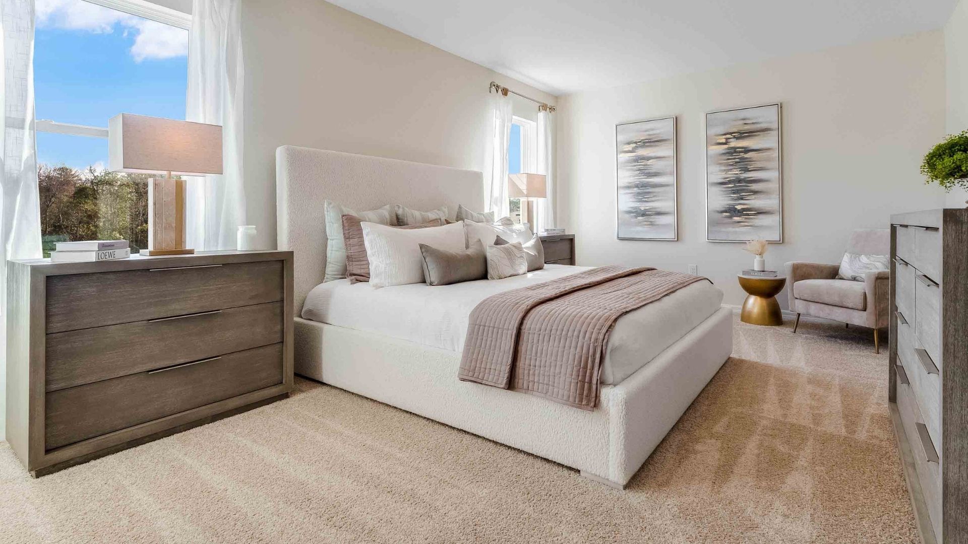 Spacious primary bedroom with king size bed, carpet flooring, natural lighting.