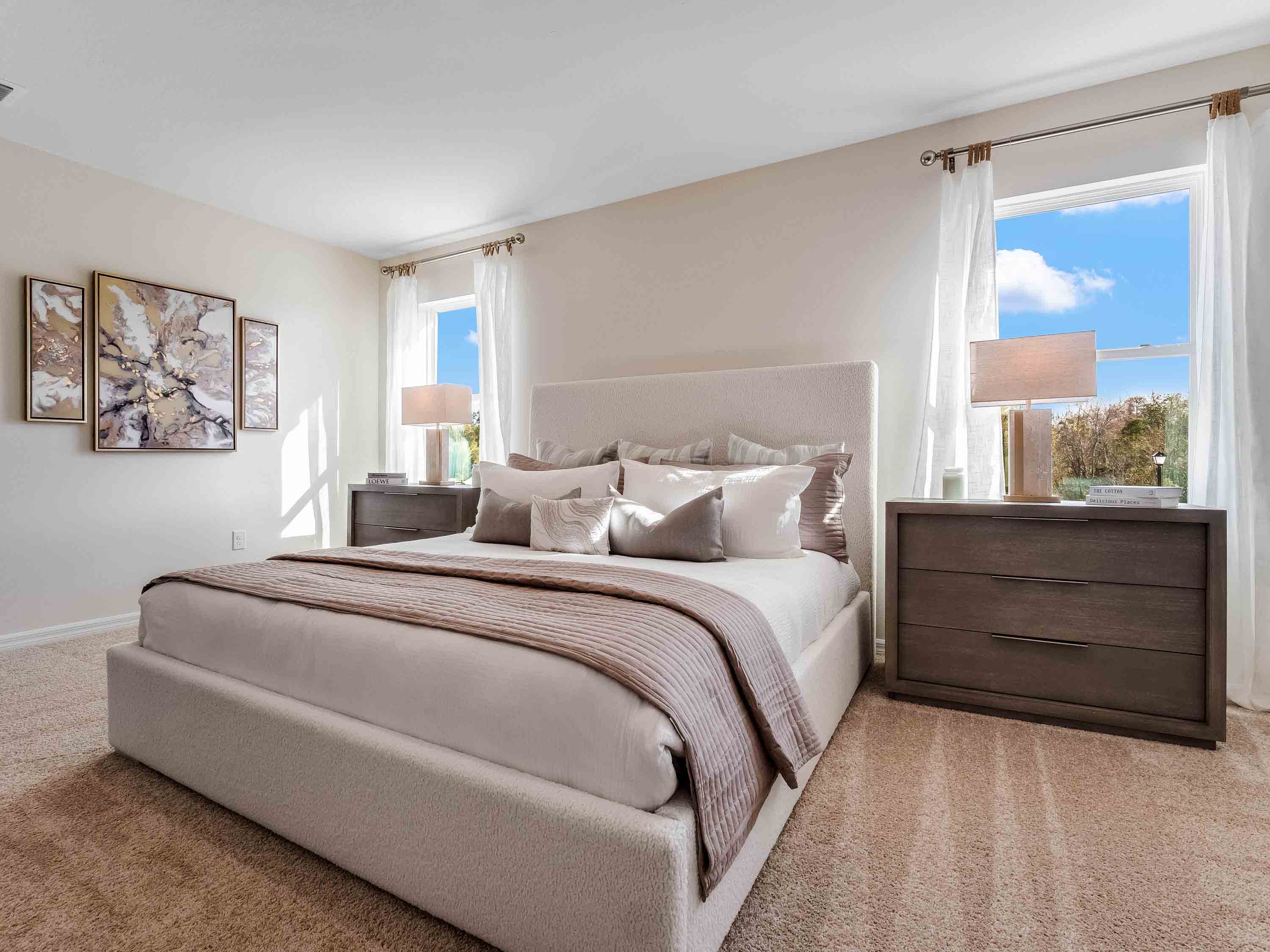 Spacious primary bedroom with king size bed, carpet flooring, natural lighting.