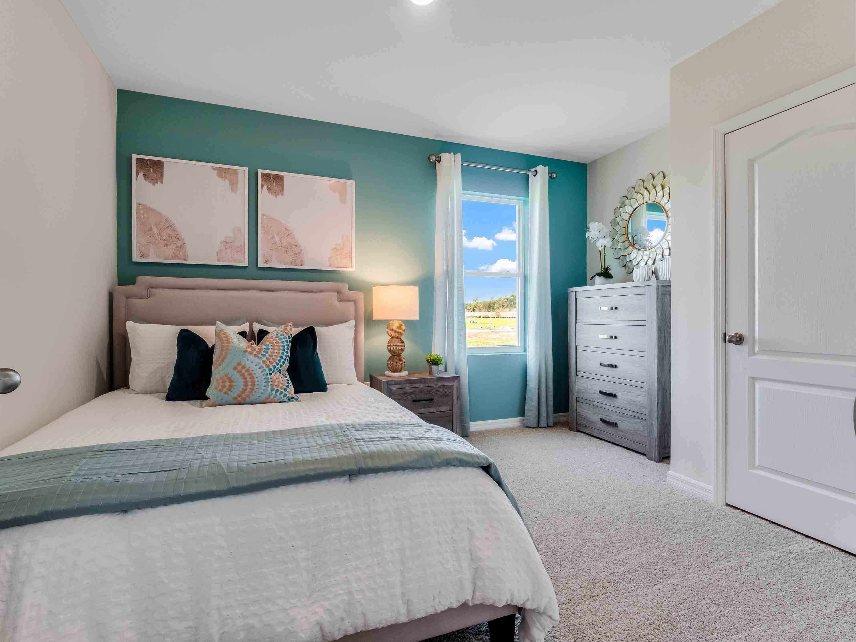 Spacious primary bedroom with king size bed, carpet flooring, natural lighting.