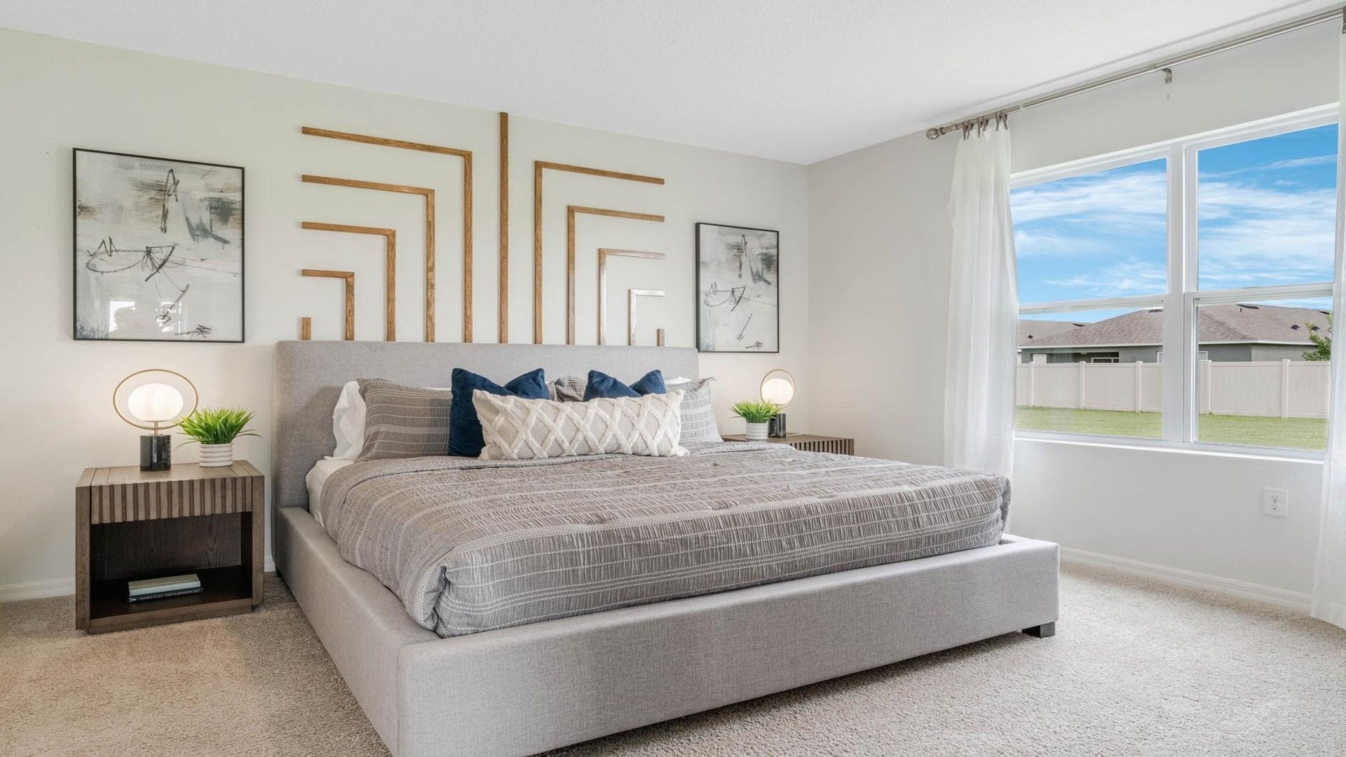 Spacious primary bedroom with king size bed, carpet flooring, natural lighting.