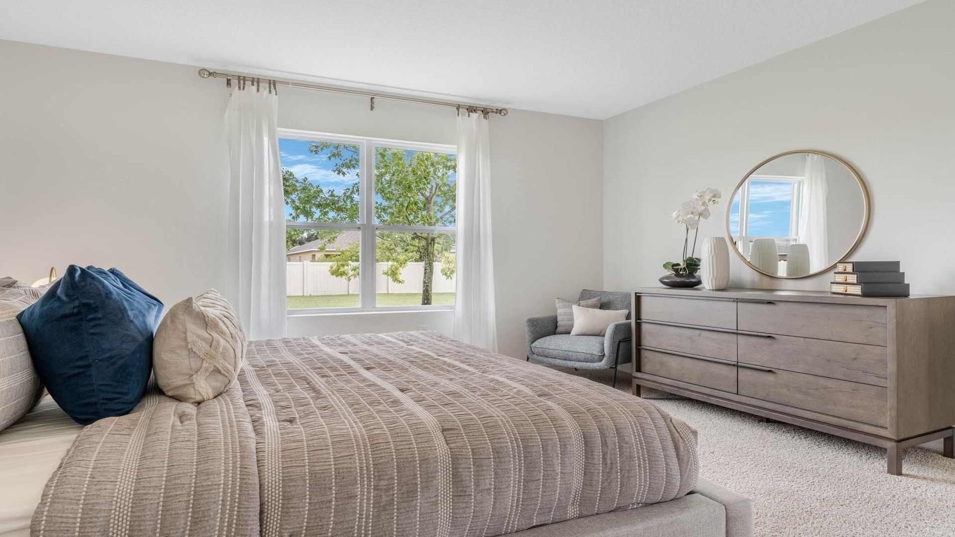 Spacious primary bedroom with king size bed, carpet flooring, natural lighting.