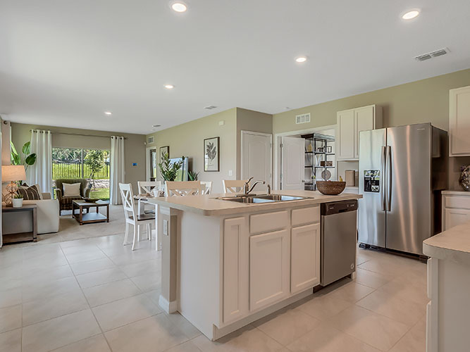 Kitchen with island seating, quartz counters, spacious pantry and stainless-steel appliances overseeing staircase