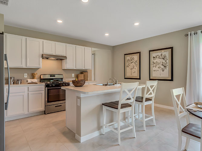 Kitchen with island seating, quartz counters, spacious pantry and stainless-steel appliances overseeing staircase