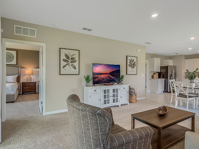 Living area with couch seating, entertainment system overseeing kitchen and dinette