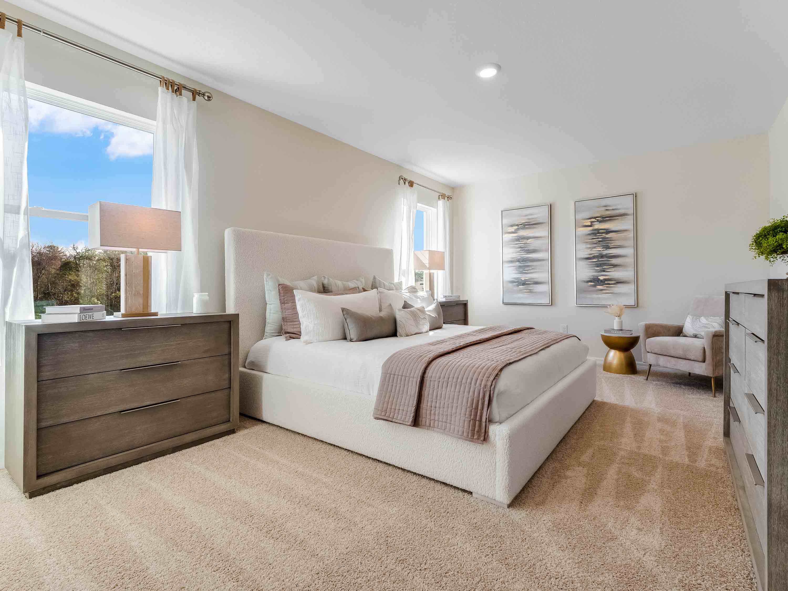 Spacious primary bedroom with king size bed, carpet flooring, natural lighting and a walk in closet.