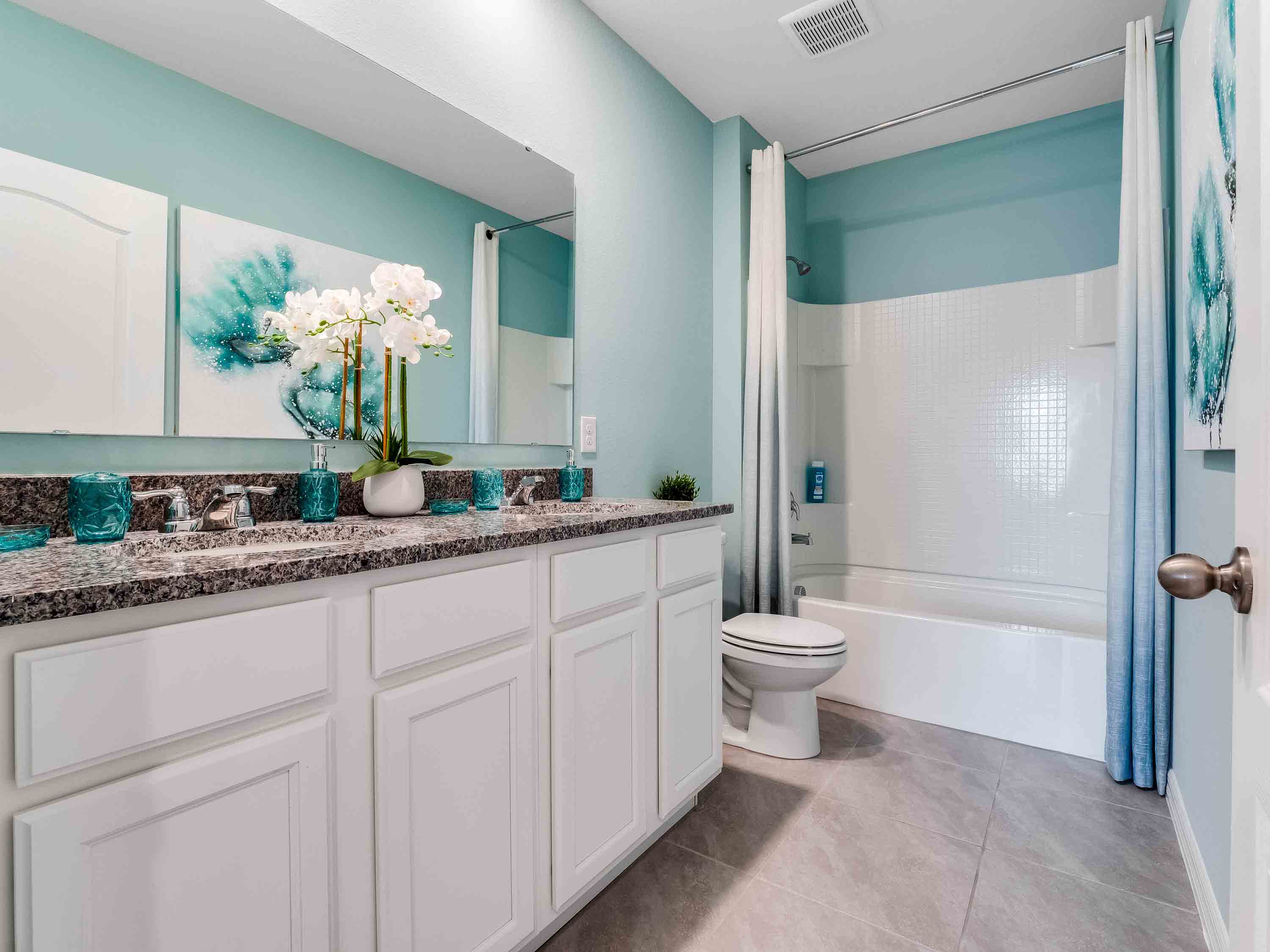 Modern bathroom with double vanity sinks, large wall mirror, cabinets and granite countertops.
