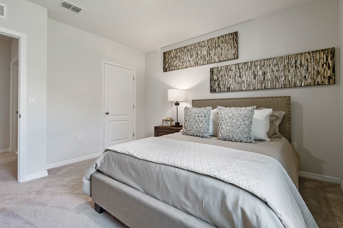 Guest bedroom with bed, nighstand, desk, and natural lighting with spacious closet.