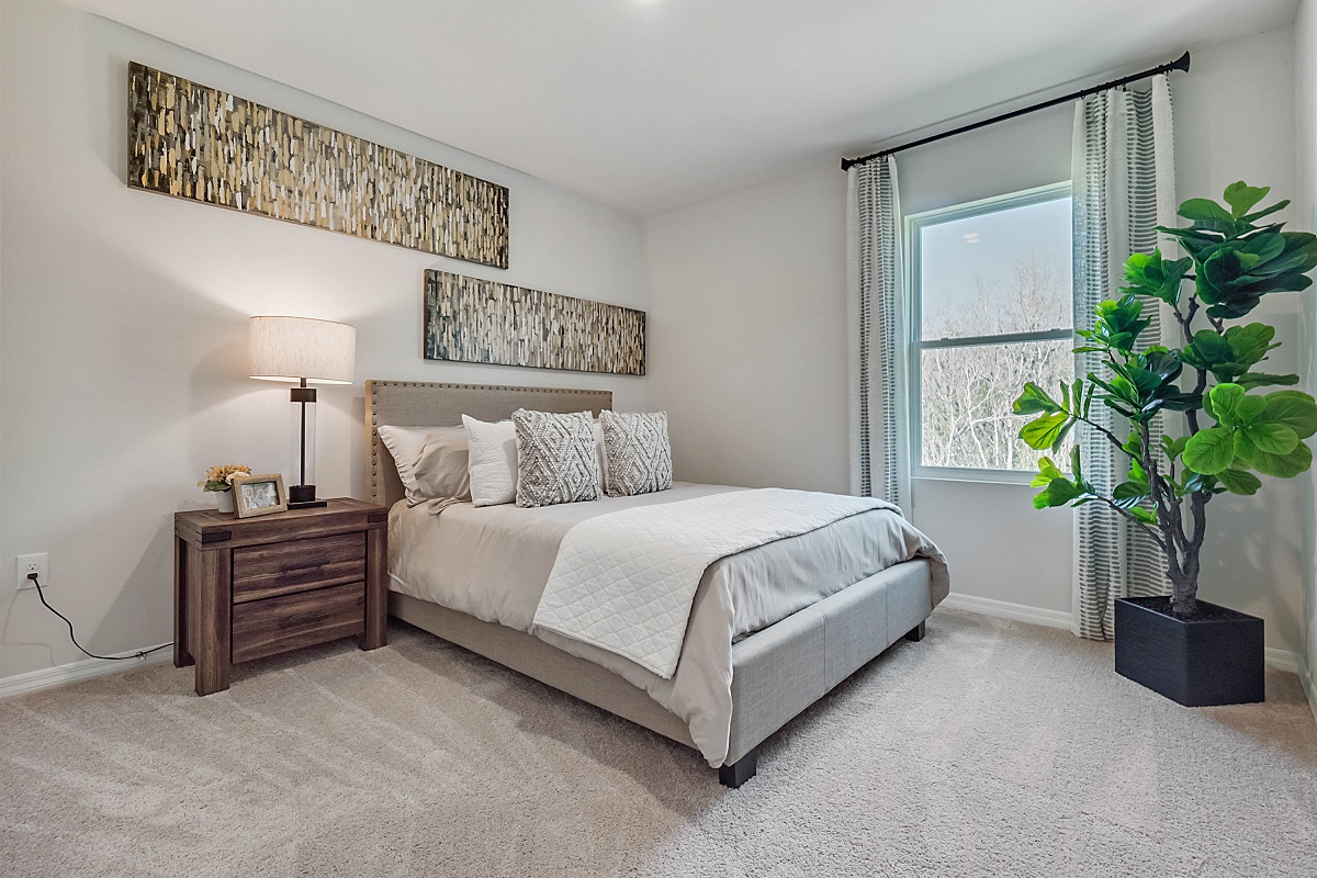 Guest bedroom with bed, nighstand, desk, and natural lighting with spacious closet.