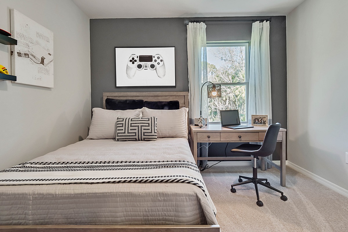 Guest bedroom with bed, nighstand, desk, and natural lighting with spacious closet.