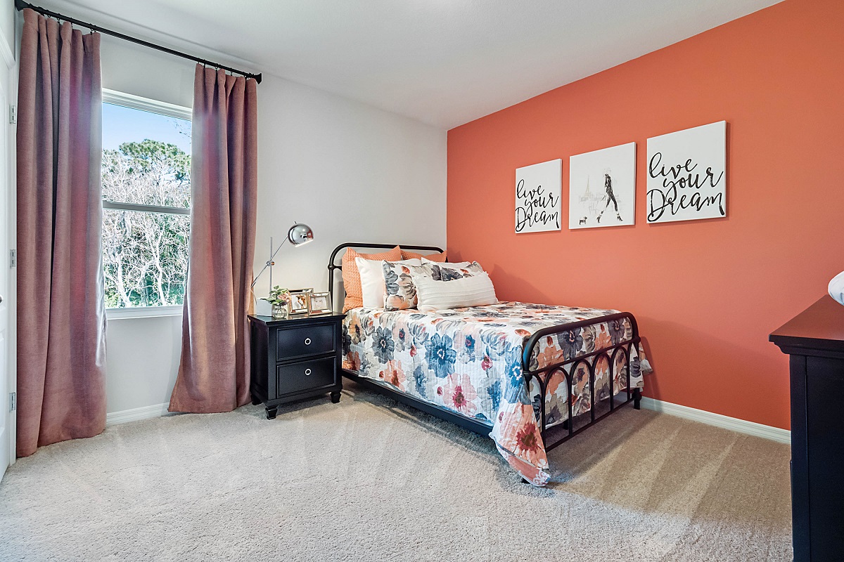 Guest bedroom with bed, nighstand, desk, and natural lighting with spacious closet.