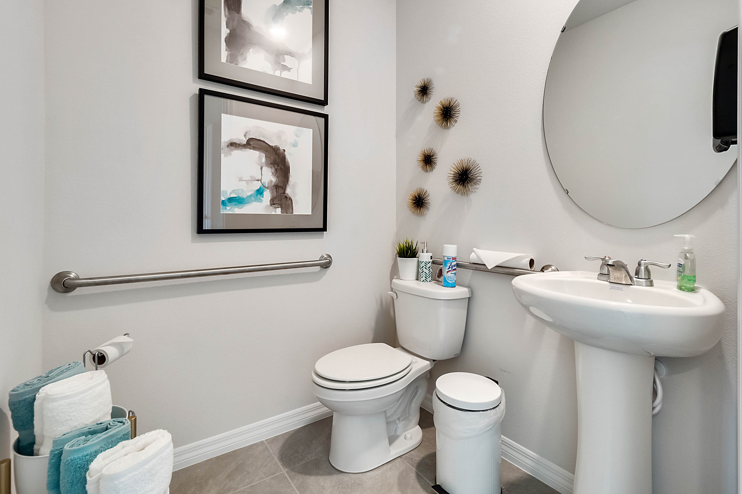 Guest bathroom showing single vanity sinks with quartz countertops, large mirror, and toilet.