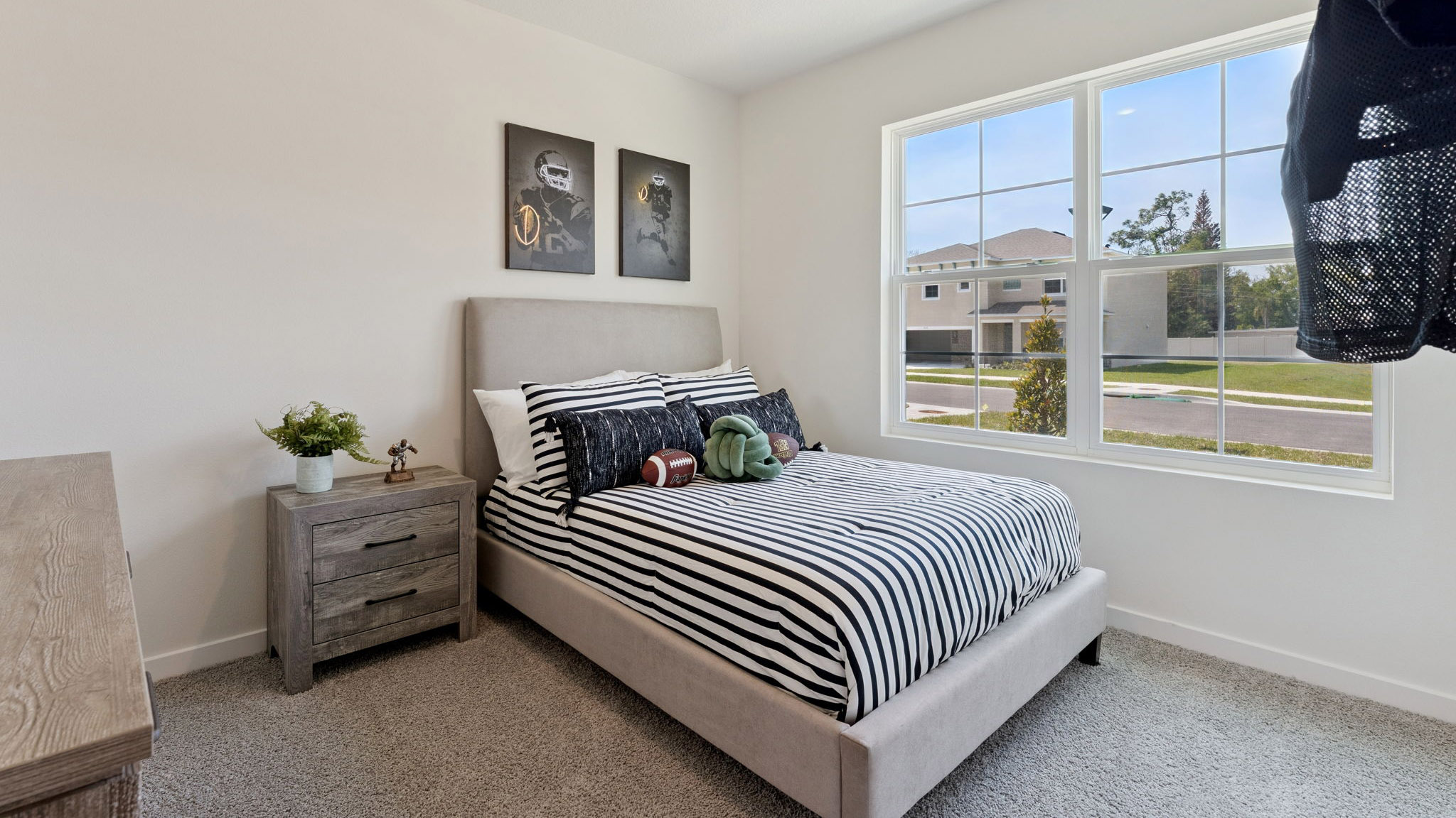 Spacious primary bedroom with king size bed, carpet flooring, natural lighting.