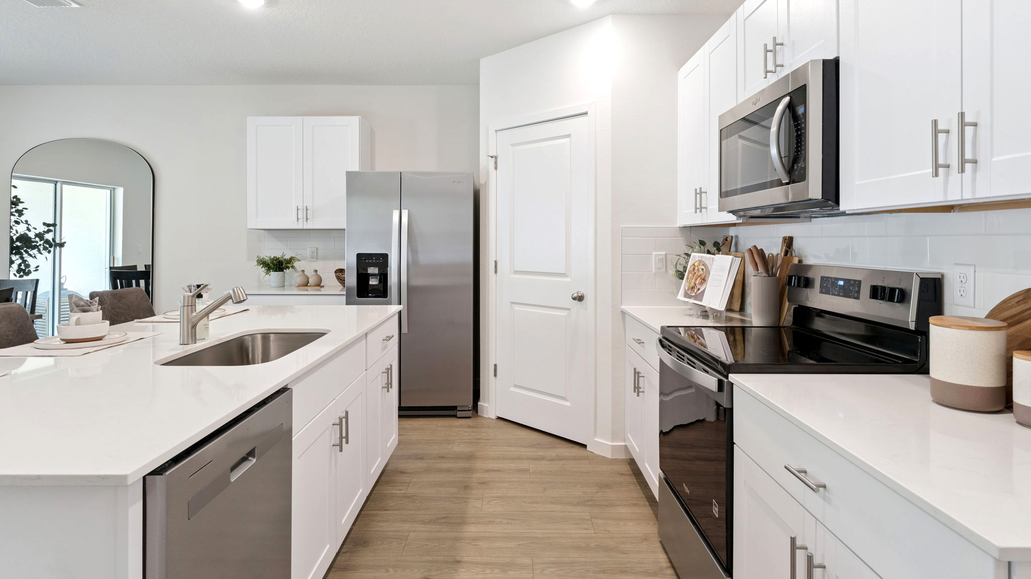 Kitchen with island seating, quartz counters, spacious pantry and stainless steel appliances.