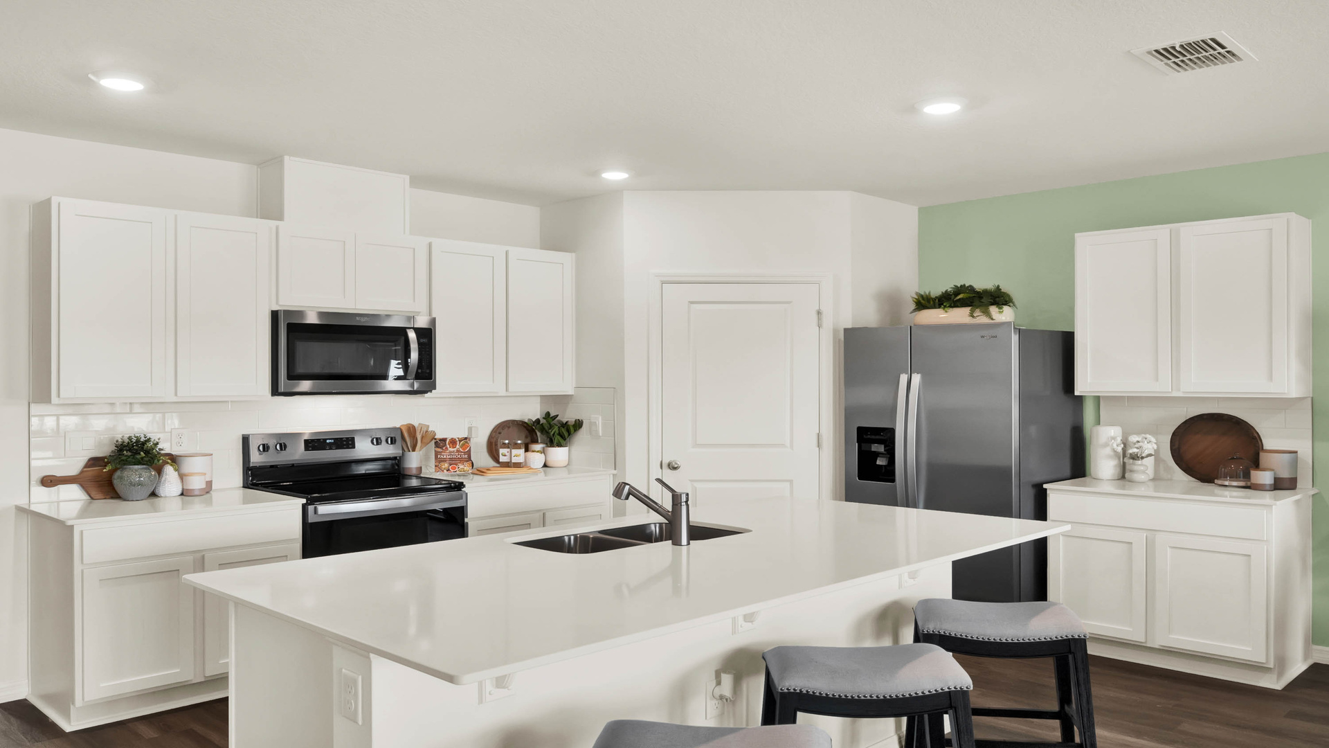 Kitchen with island seating, quartz counters, spacous pantry and stainless steel appliances.