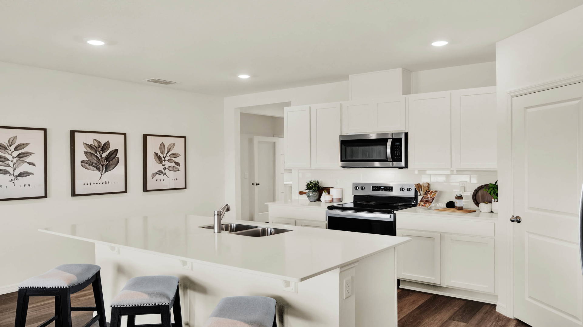 Kitchen with island seating, quartz counters, spacous pantry and stainless steel appliances.
