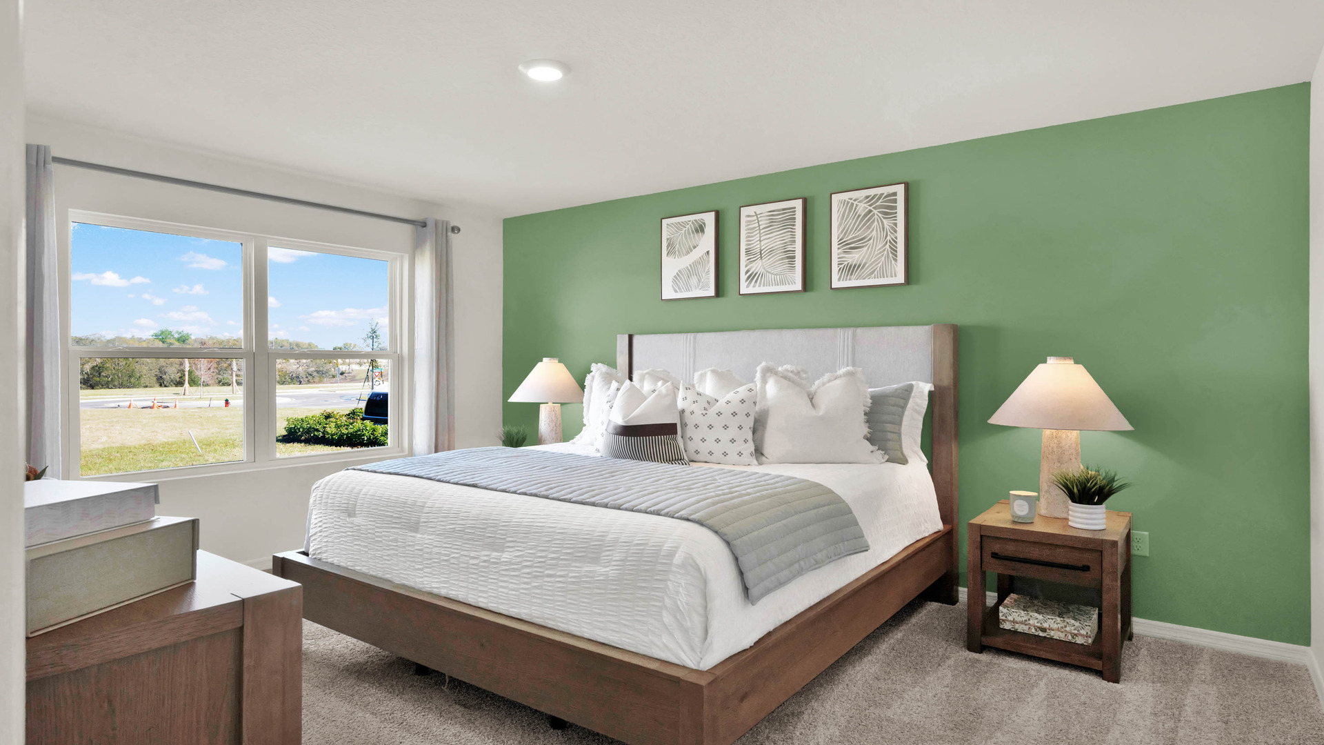 Spacious primary bedroom with king size bed, carpet flooring, natural lighting.