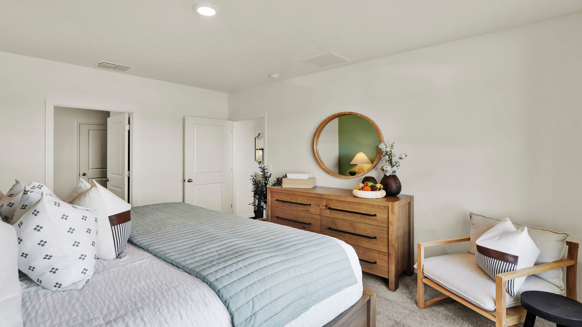 Spacious primary bedroom with king size bed, carpet flooring, natural lighting.