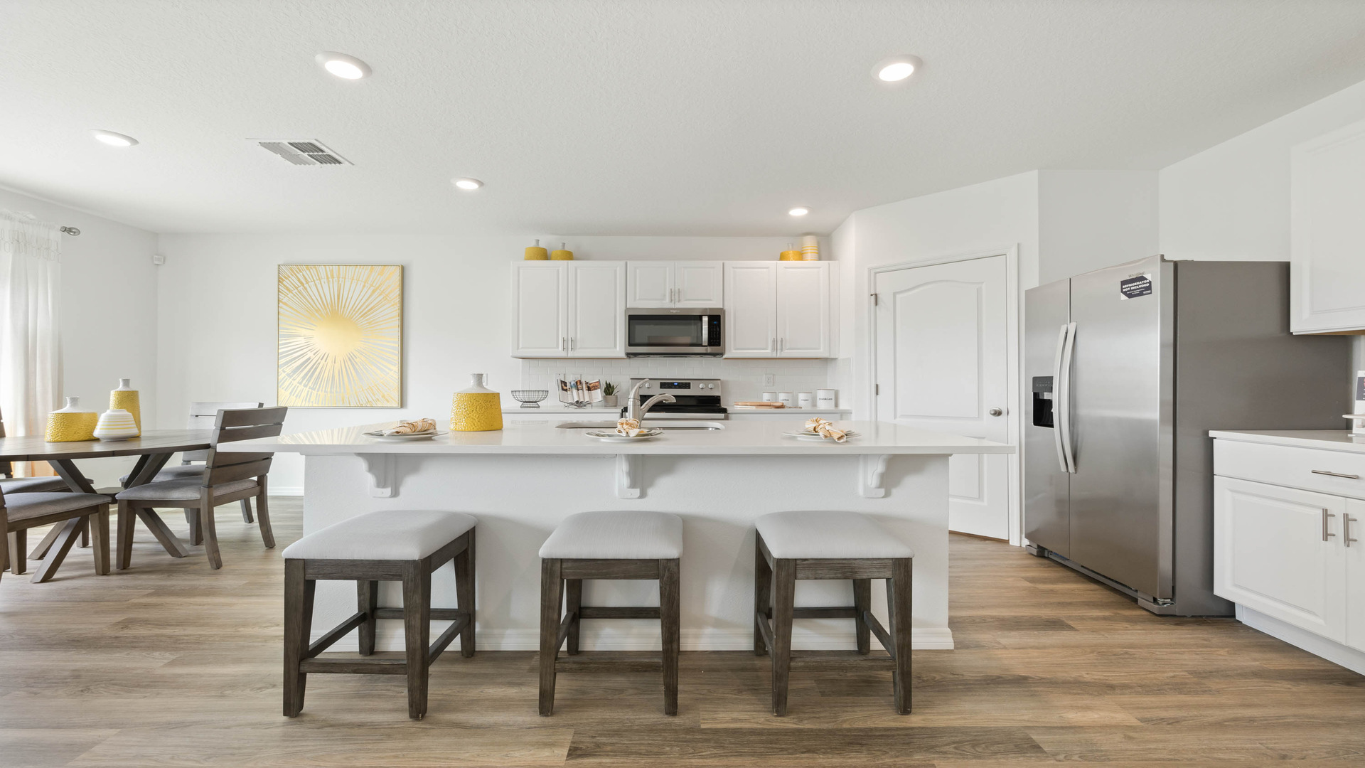 Kitchen with island seating, quartz counters, spacious pantry and stainless-steel appliances.