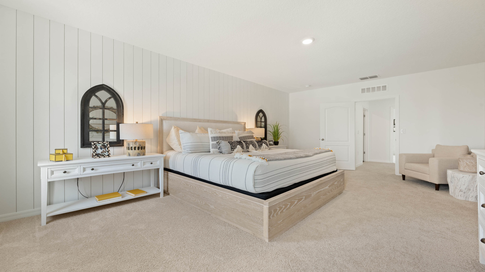 Spacious primary bedroom with king size bed, carpet flooring, natural lighting.