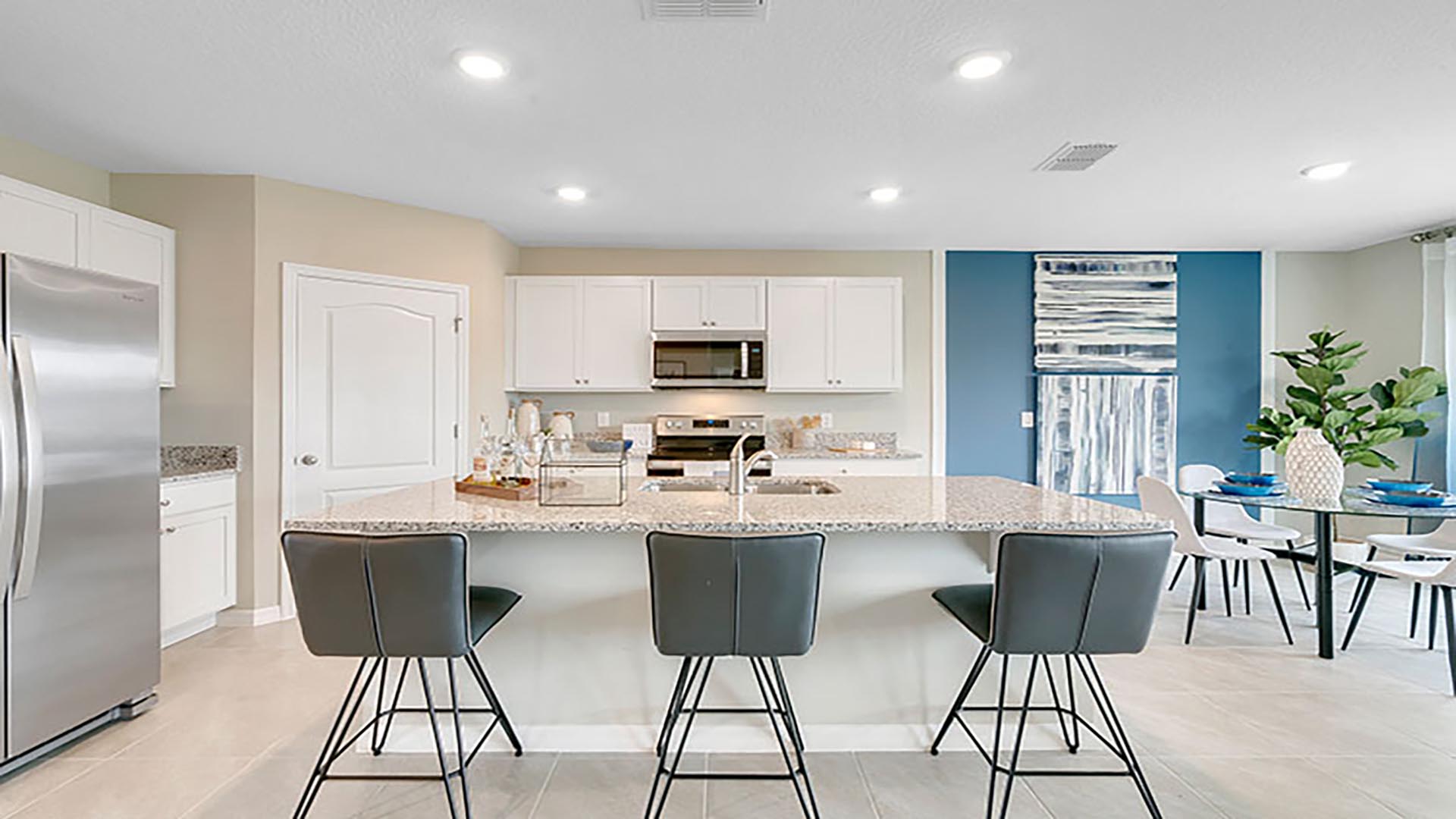 Kitchen with island seating, quartz counters, spacious pantry and stainless-steel appliances.