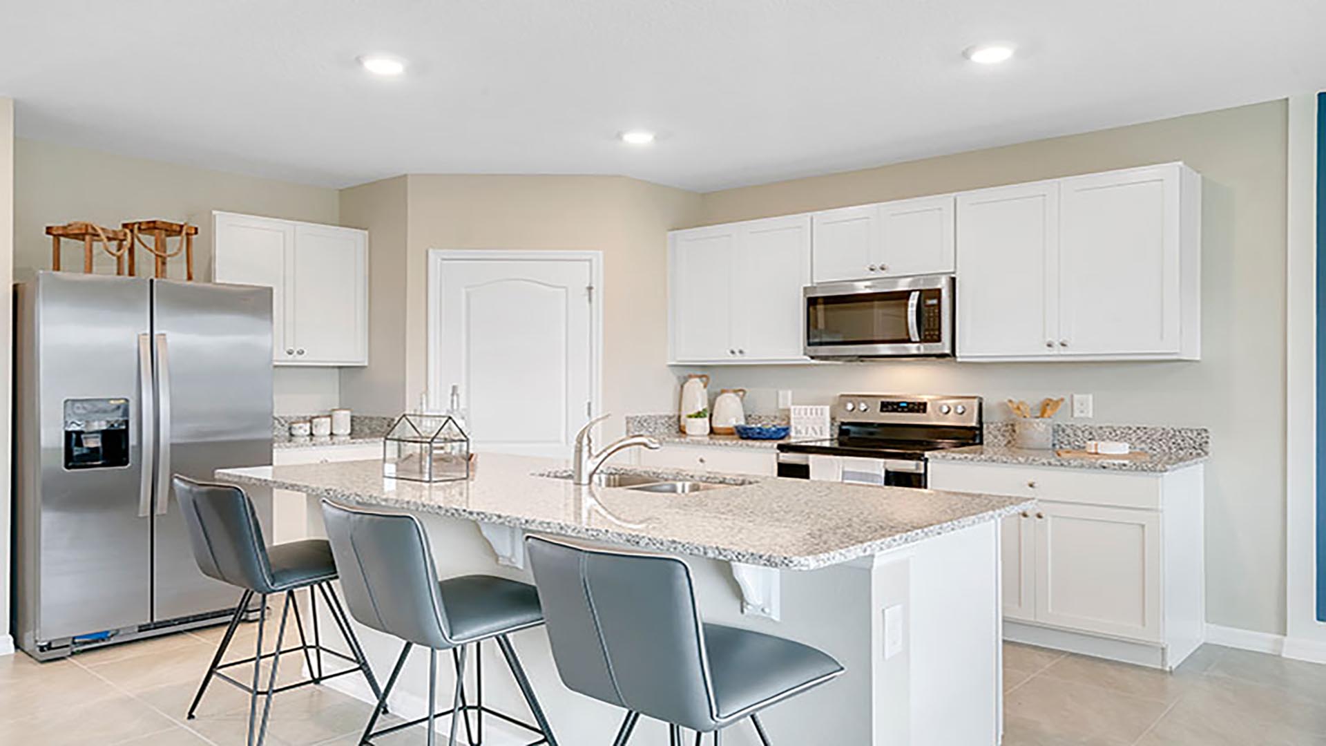 Kitchen with island seating, quartz counters, spacious pantry and stainless-steel appliances.