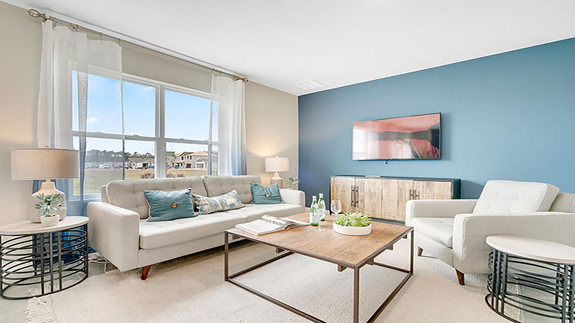Living area with couch seating, natural lighting adjacent to kitchen and dinette.