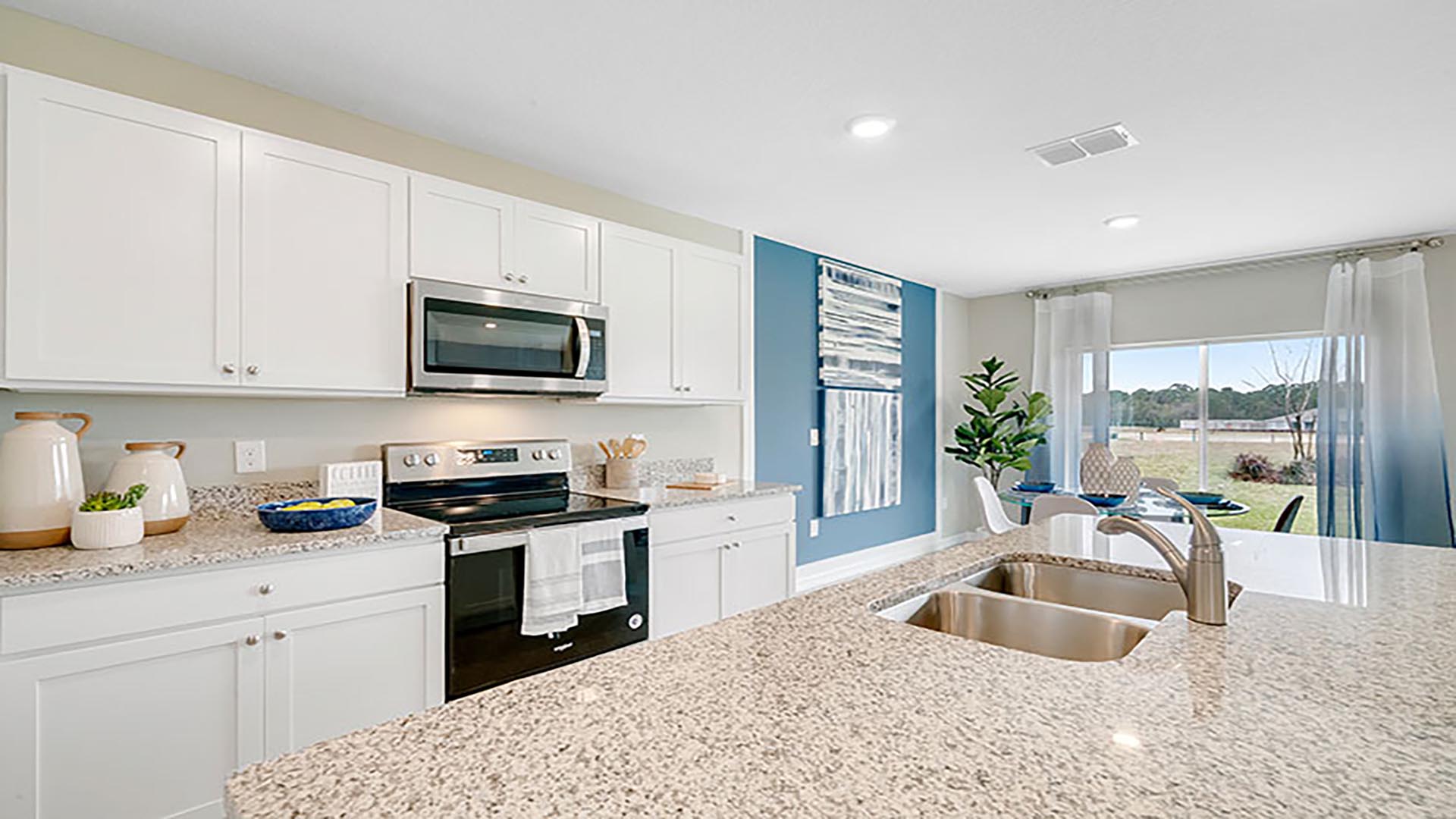 Kitchen with island seating, quartz counters, spacious pantry and stainless-steel appliances.