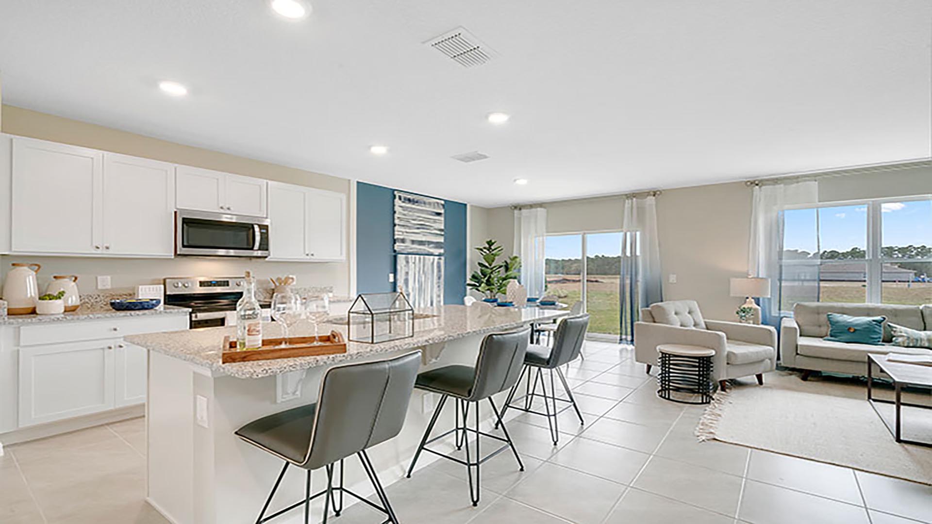 Kitchen with island seating, quartz counters, spacious pantry and stainless-steel appliances.