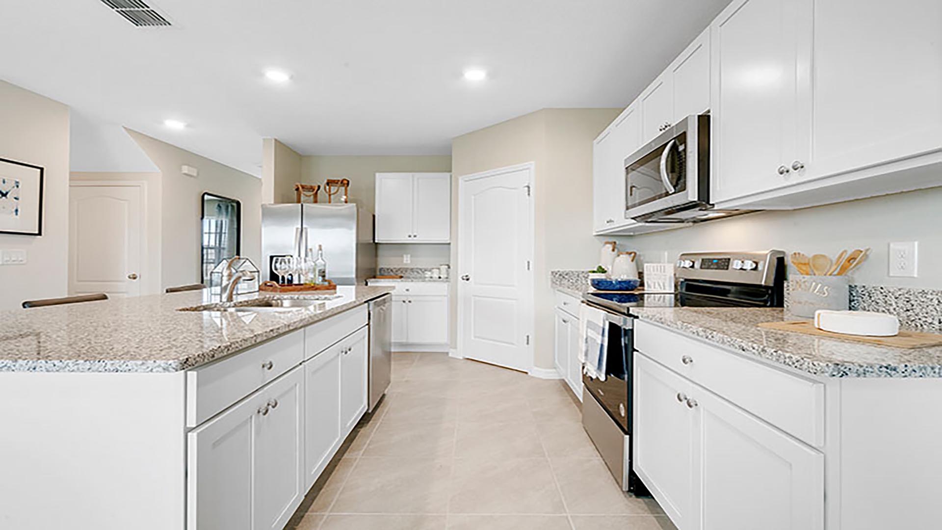 Kitchen with island seating, quartz counters, spacious pantry and stainless-steel appliances.