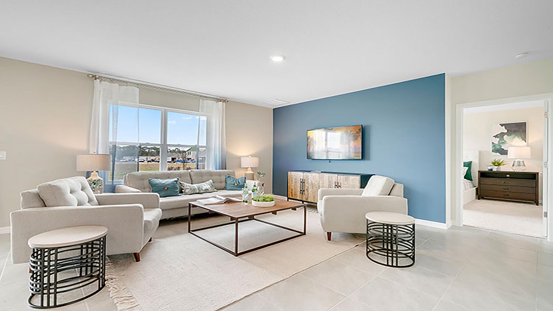 Living area with couch seating, natural lighting adjacent to kitchen and dinette.