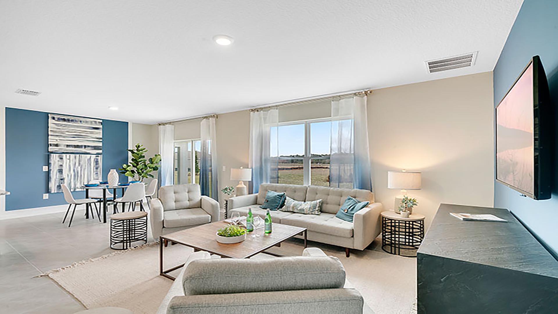 Living area with couch seating, natural lighting adjacent to kitchen and dinette.