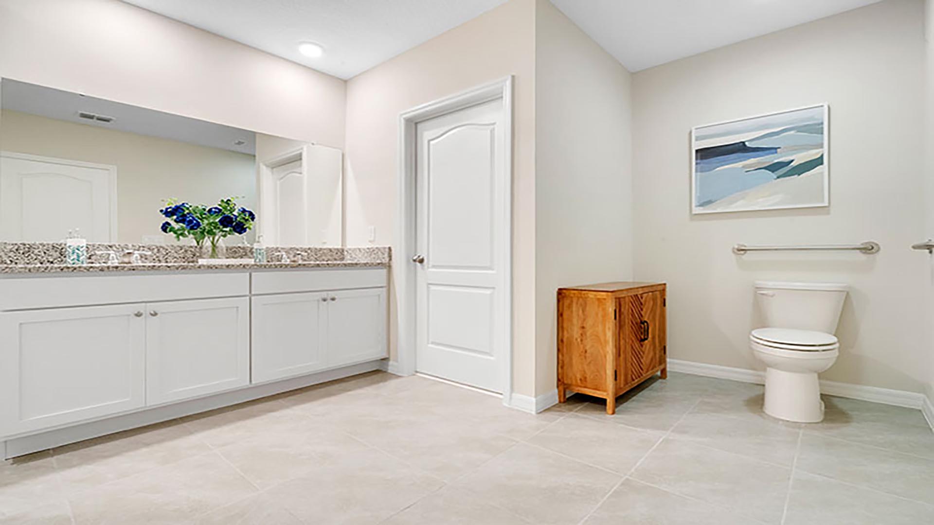 Modern bathroom with double vanity sinks, large wall mirror, cabinets and granite countertops.
