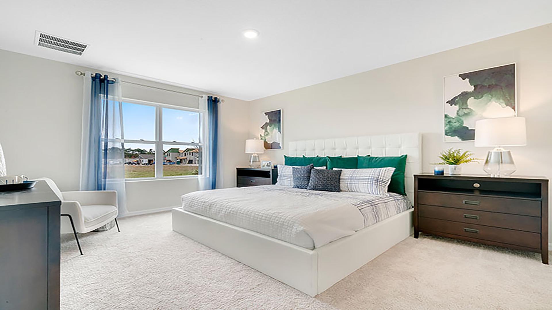 Spacious primary bedroom with king size bed, carpet flooring, natural lighting.