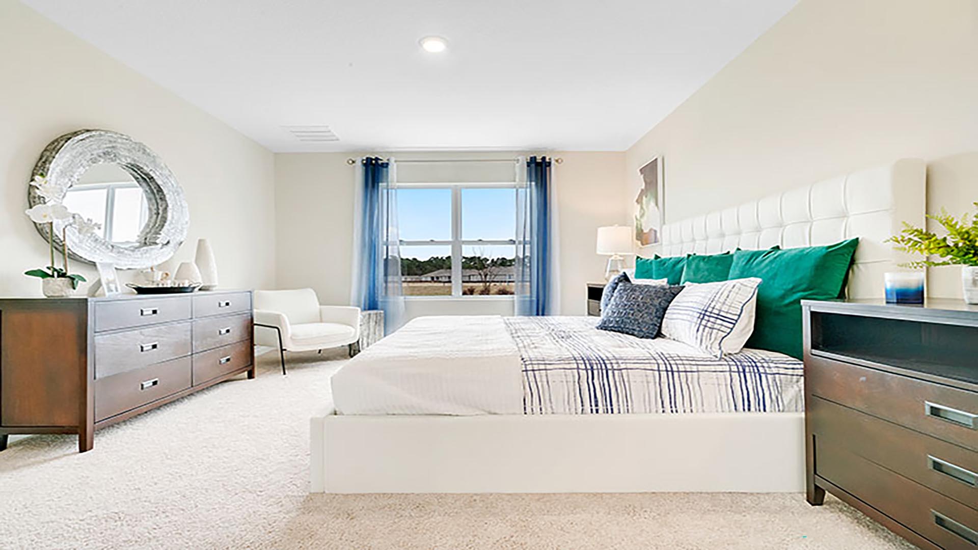 Spacious primary bedroom with king size bed, carpet flooring, natural lighting.