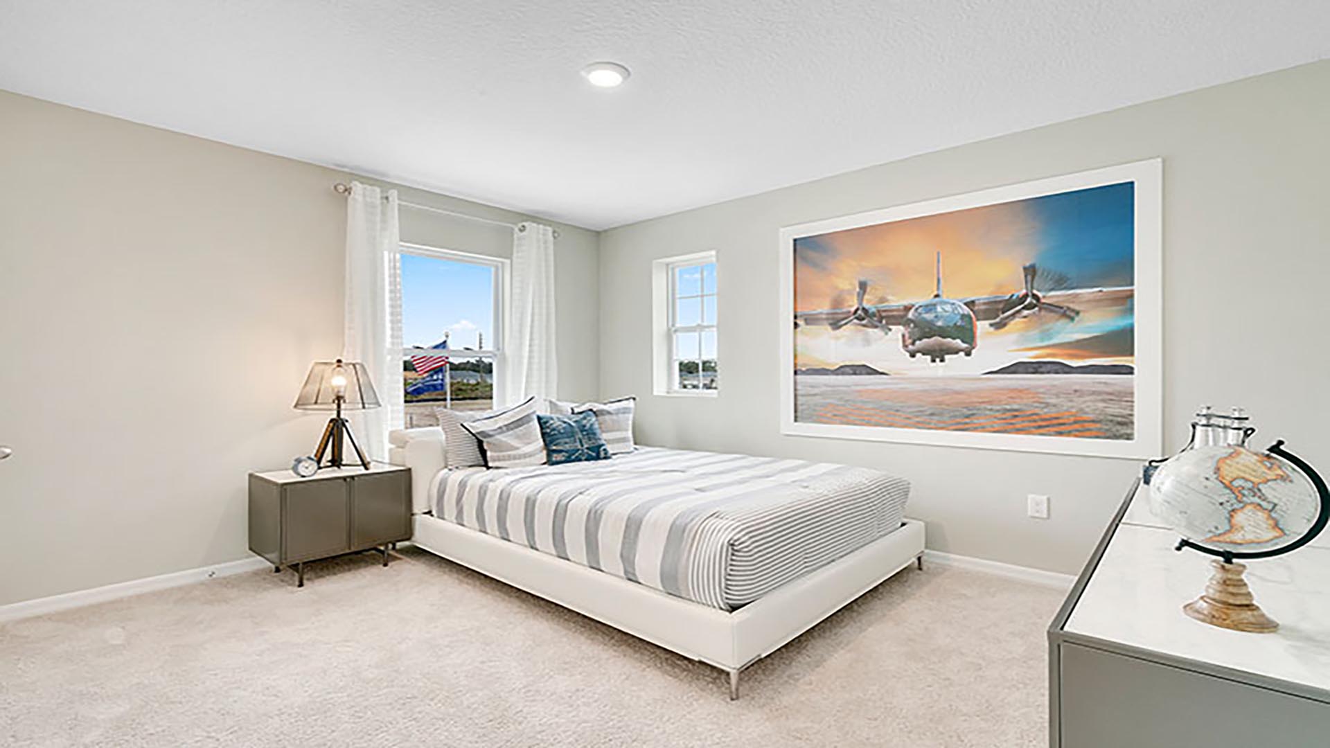 Spacious primary bedroom with king size bed, carpet flooring, natural lighting.