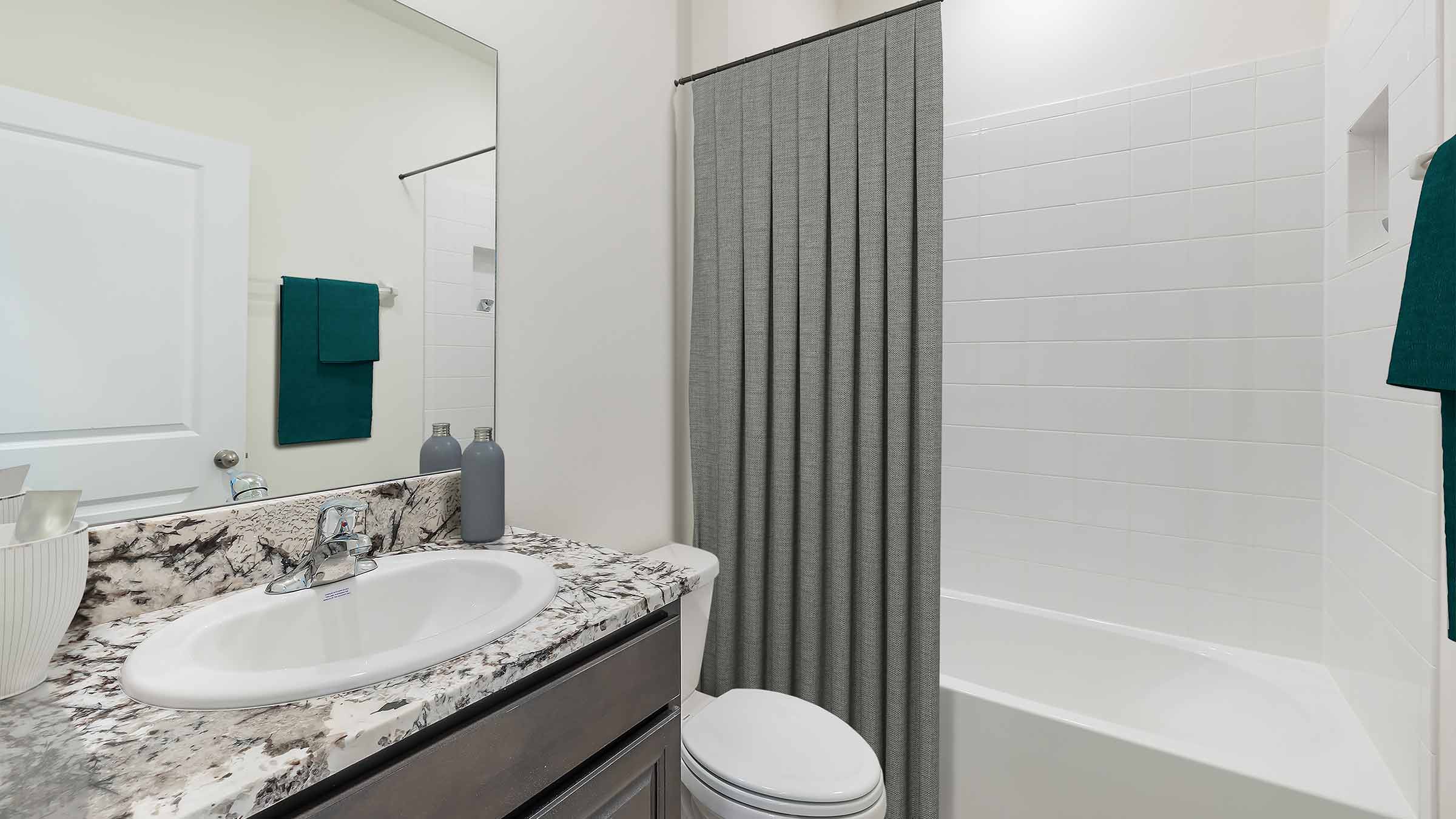 Bathroom with shower and sink and gray cabinet