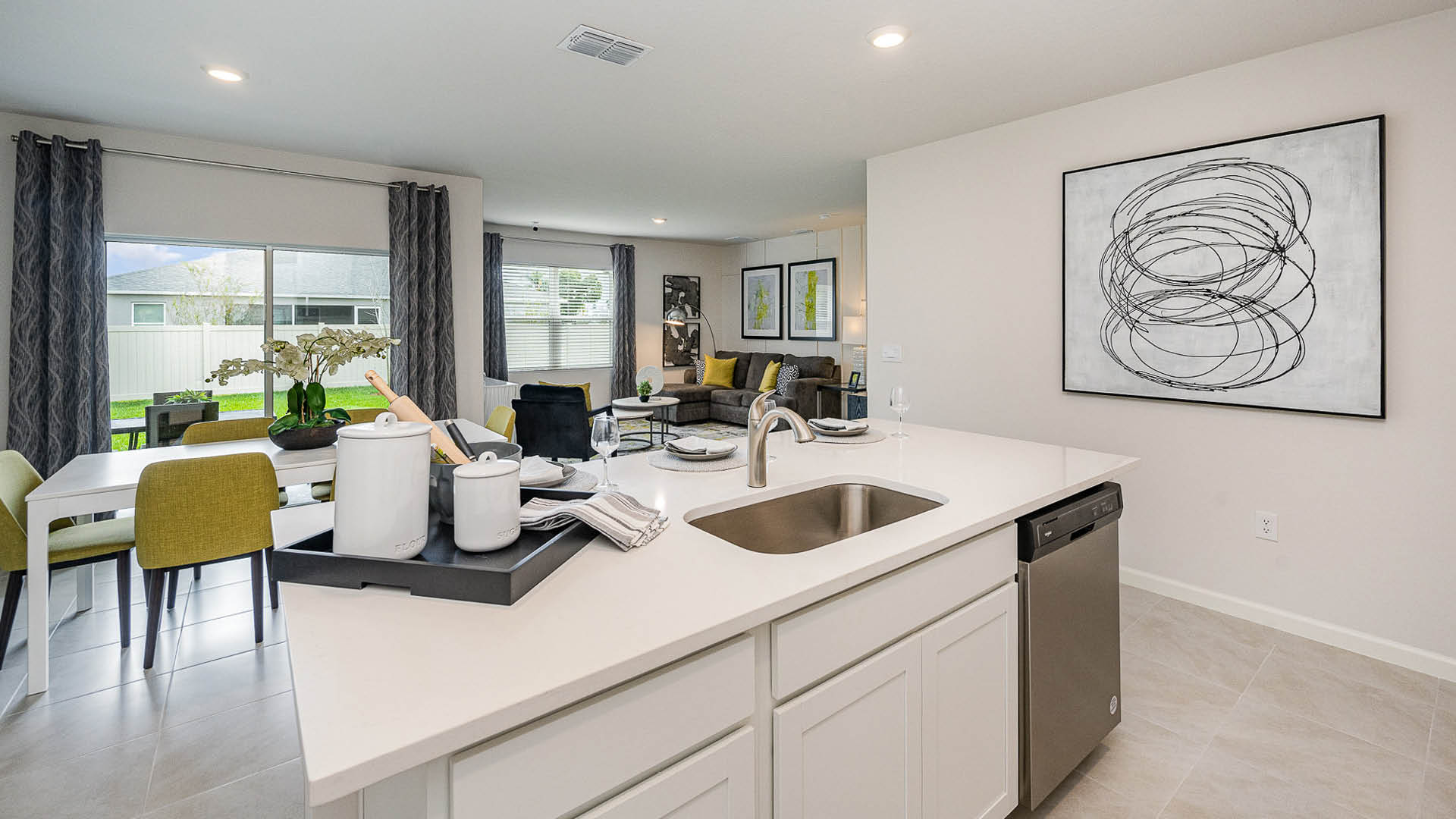 Modern kitchen with quartz countertops, stainless appliances, and stylish decor, overlooking a dining area with green chairs.