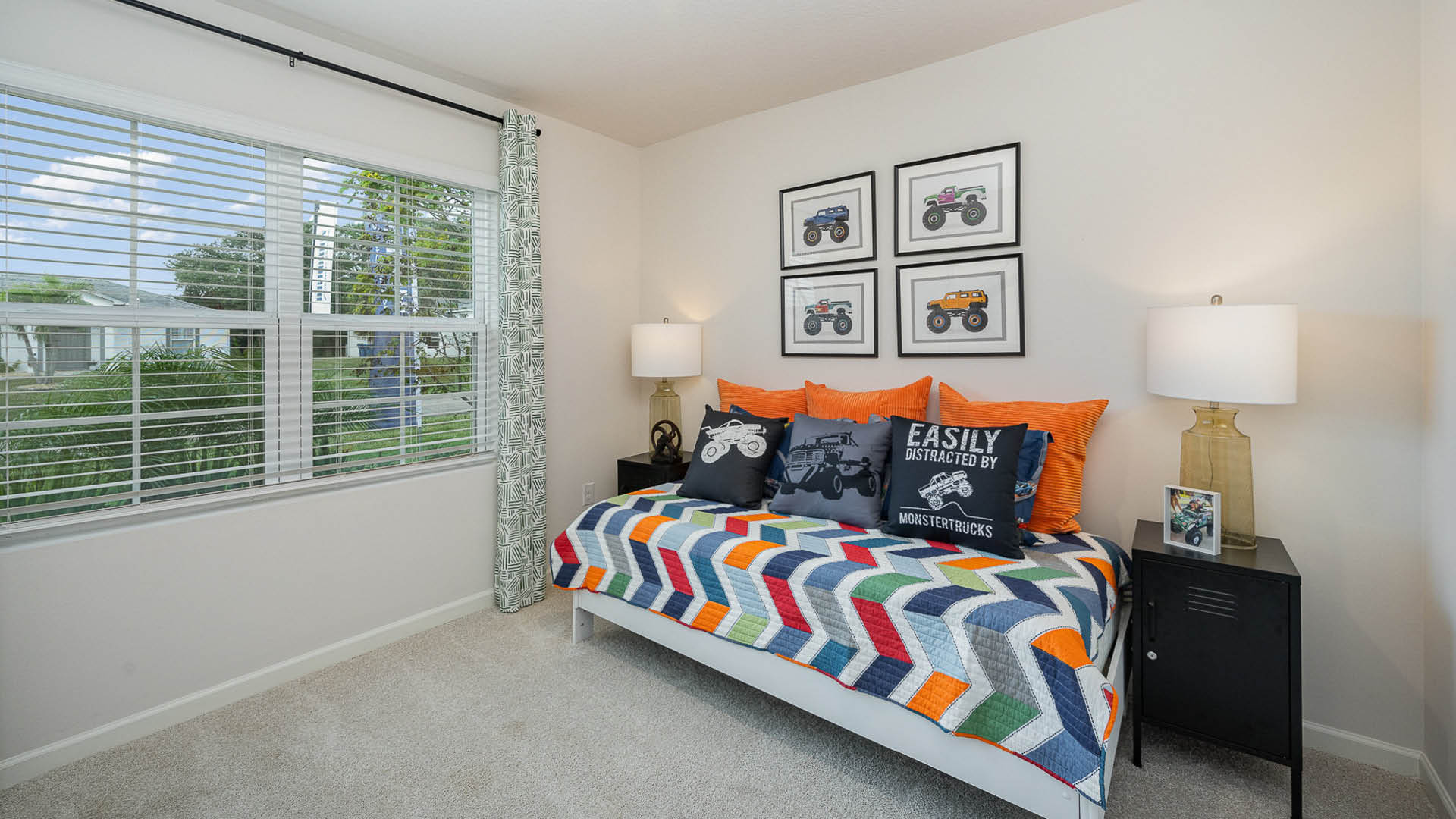 Bright bedroom featuring a colorful quilt, monster truck decor, and a large window with sheer blinds, creating a cheerful ambiance.Bright entryway featuring a nature-themed painting, a sleek console table with plants, and a view into a cozy living area.