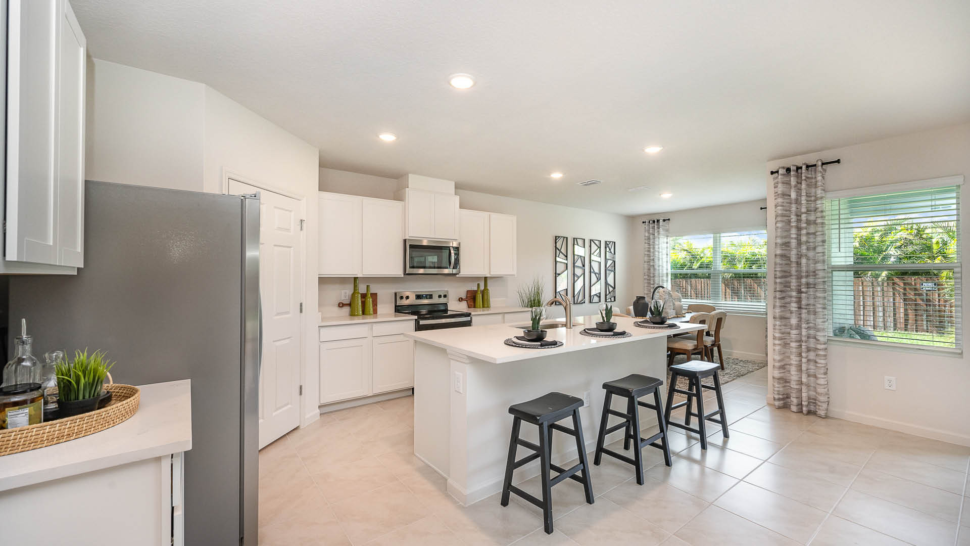 Spacious, open-concept living area featuring a central column, large windows, and smooth tile flooring in a light, neutral palette.