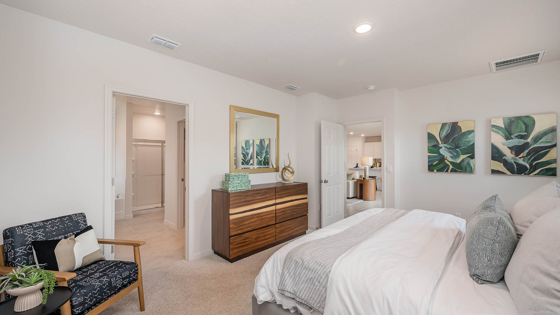 Cozy bedroom featuring a metal bed frame, colorful pillows, patterned art, and decorative plants, with soft lighting and draped curtains.
