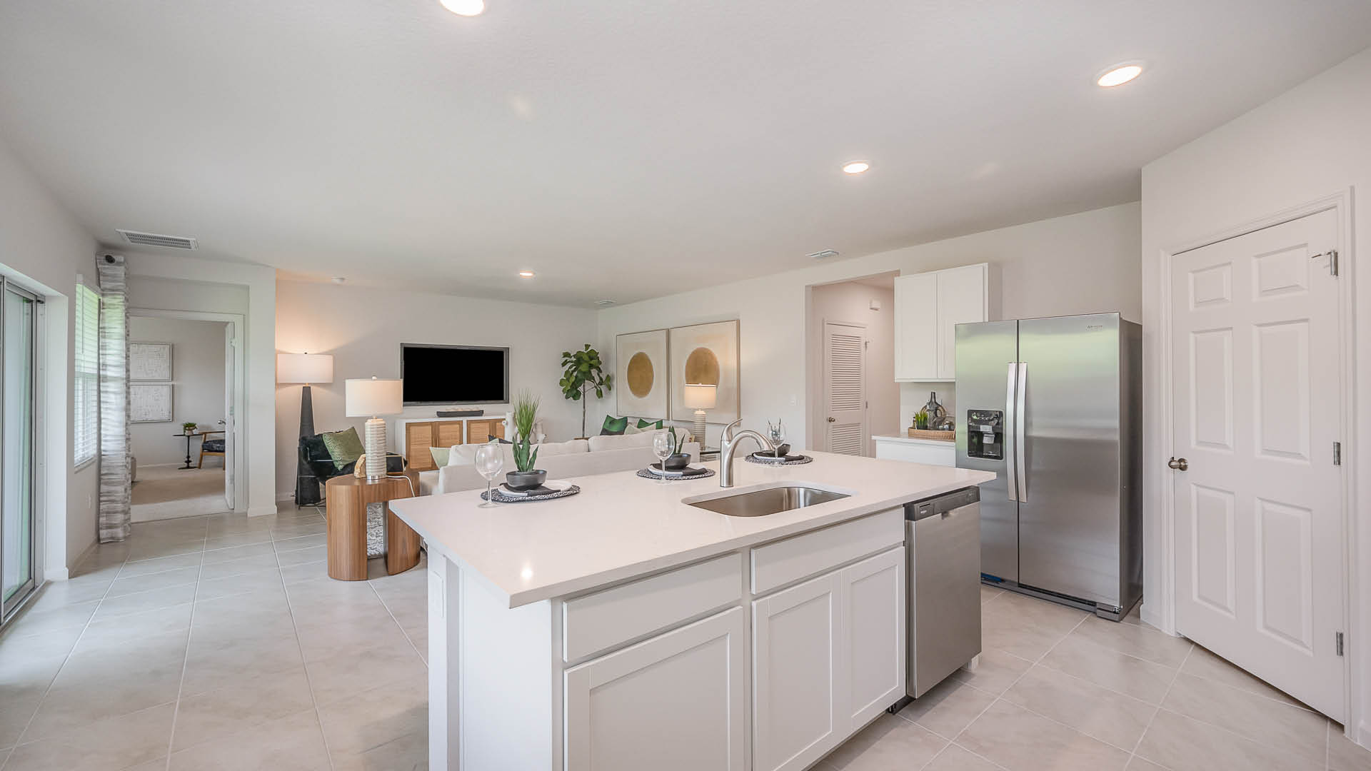 Modern kitchen featuring white cabinetry, stainless steel appliances, a large quartz countertop, and ample natural light from nearby windows.