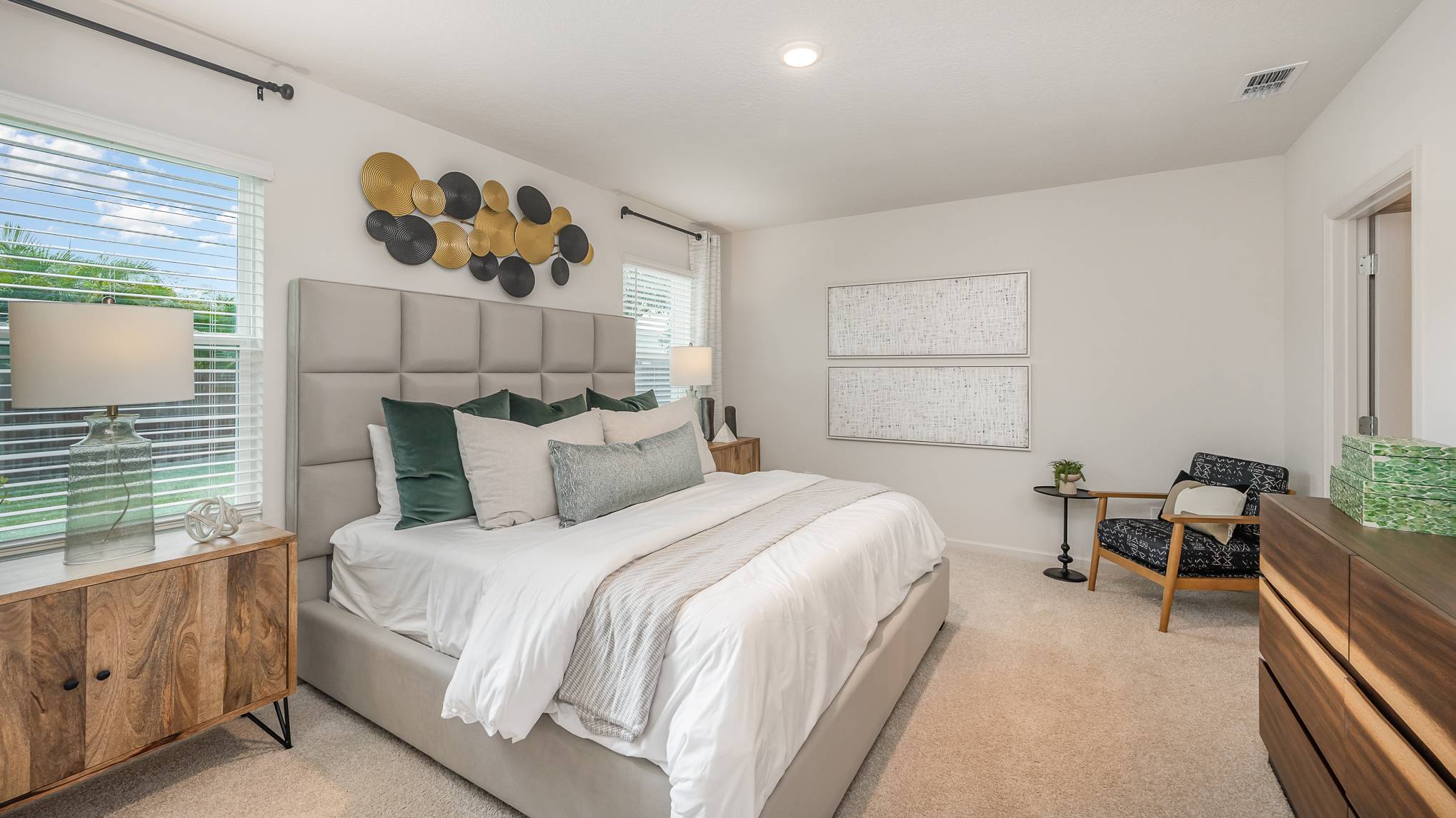 Modern bedroom featuring a plush bed with decorative pillows, elegant wall art, and large windows creating a bright, welcoming ambiance.