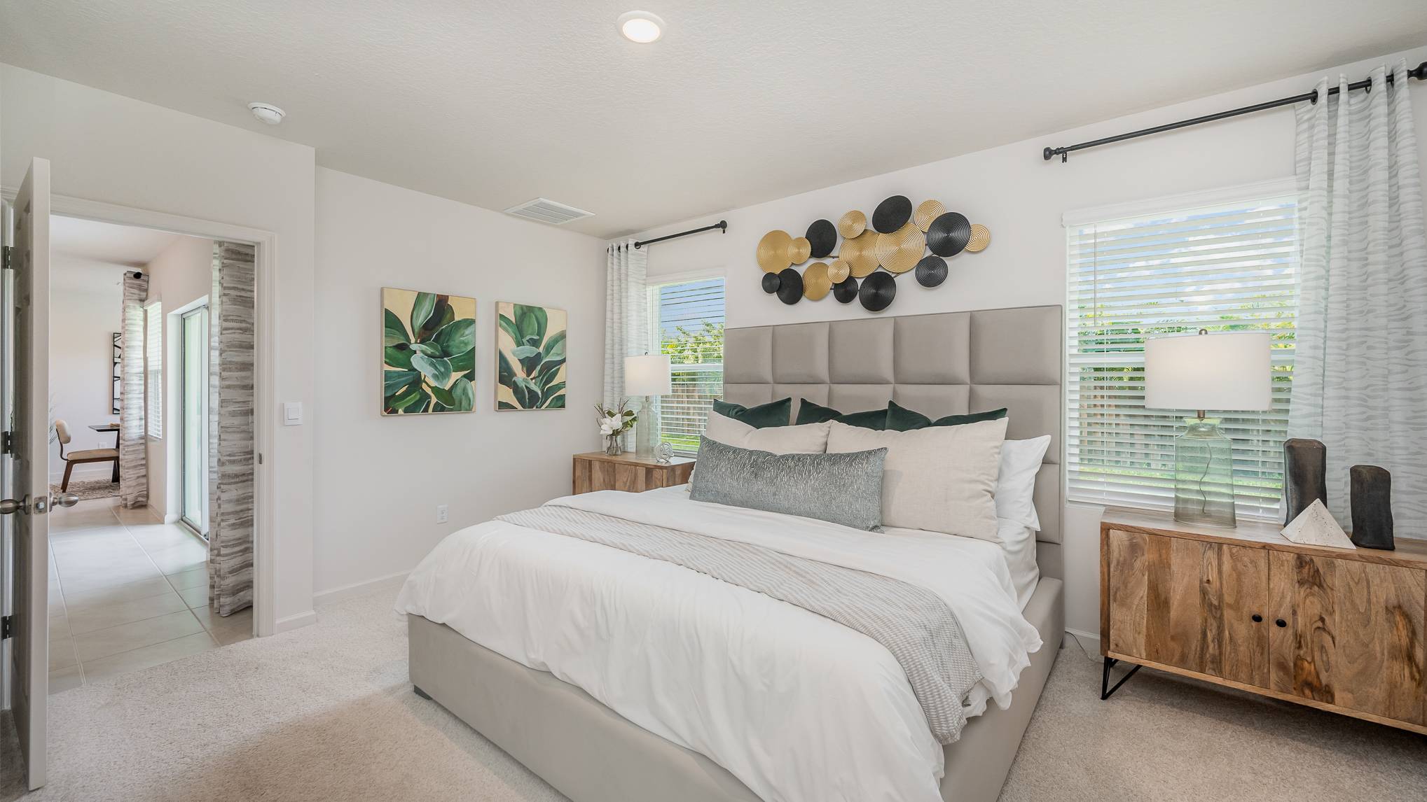 Cozy modern bedroom with a plush bed, decorative pillows, stylish wall art, and natural light from a window, creating a serene atmosphere.