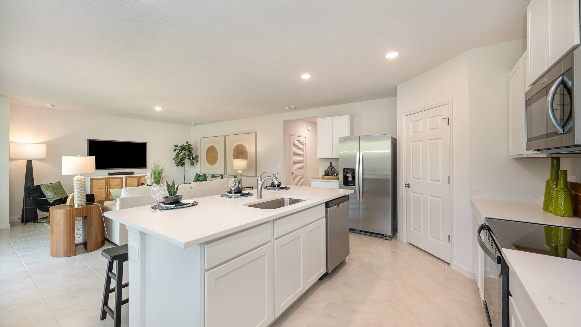 Modern kitchen and living area with white cabinetry, stainless steel appliances, and stylish furnishings in an open layout.
