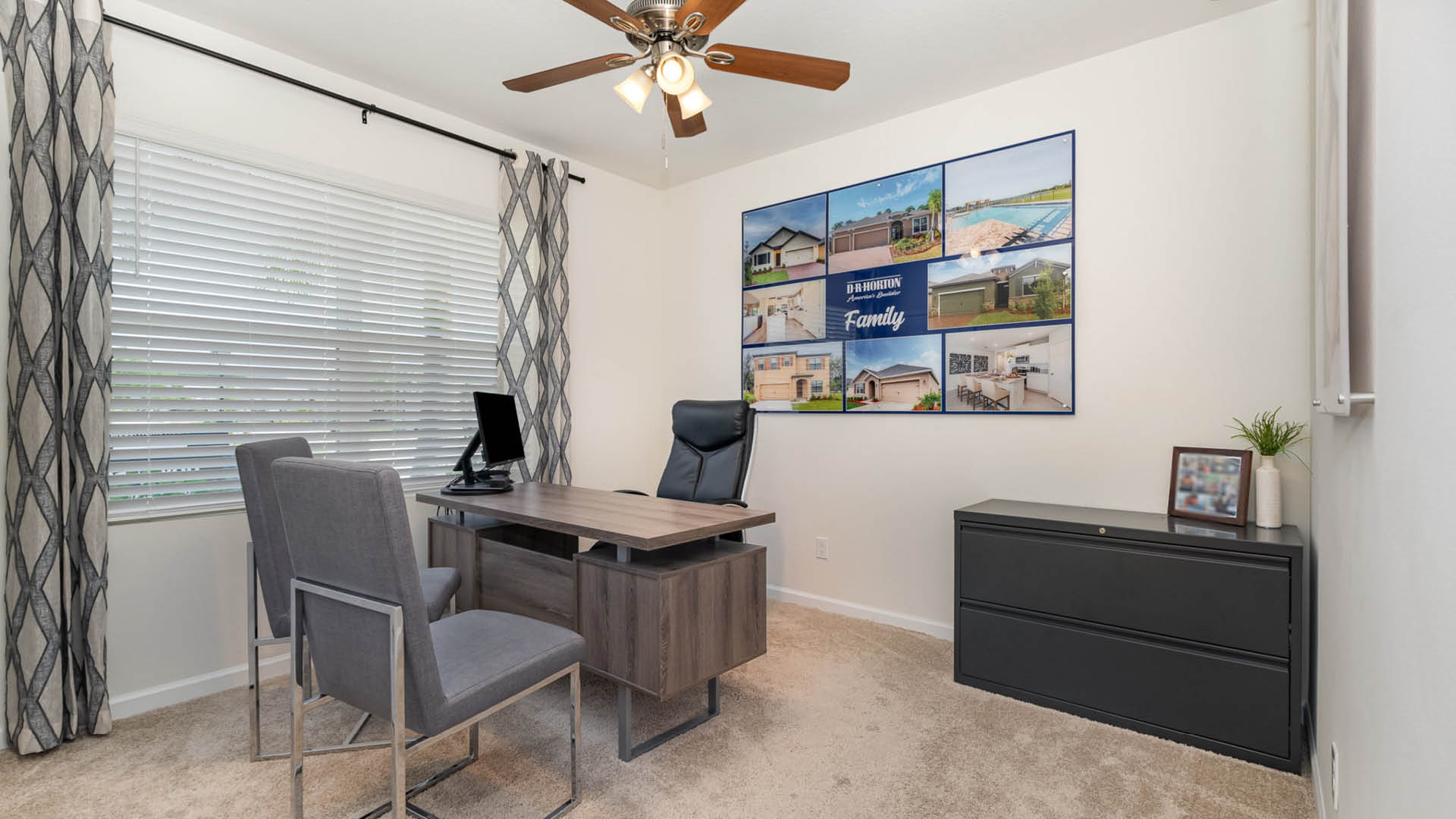 A modern home office featuring a desk, ergonomic chair, two gray chairs, and inspirational wall art. Bright, airy with window blinds.
