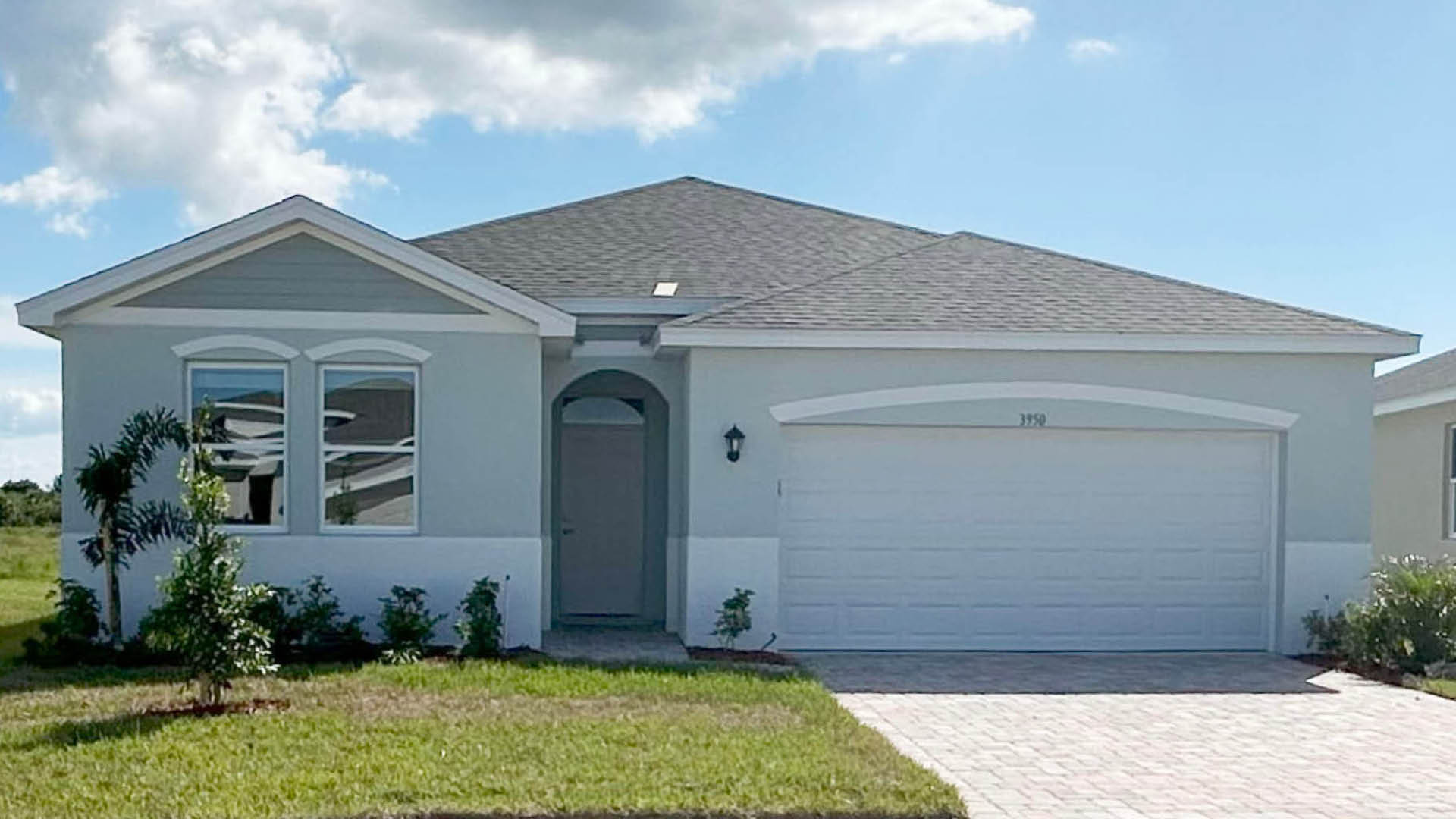 A modern single-story home with light gray exterior, a landscaped front yard, and a two-car garage.