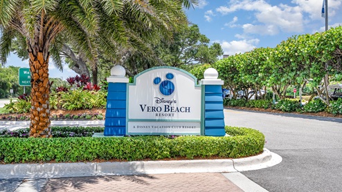 Sign for Disney's Vero Beach Resort, featuring a Mickey Mouse silhouette, surrounded by lush tropical landscaping and vibrant greenery.